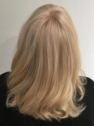 Foto del dopo: donna vista da dietro con capelli biondi di media lunghezza sani dopo il colore.