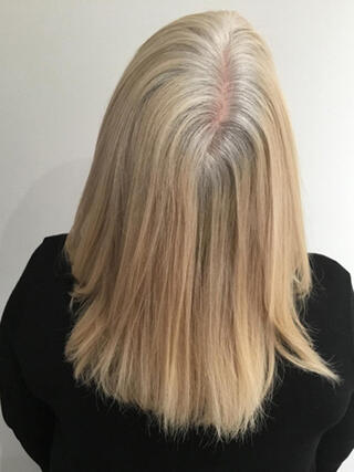 Foto del prima: donna vista da dietro con capelli biondi di media lunghezza con striature nere prima del colore.