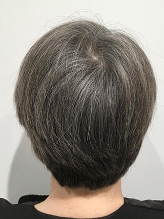 Foto del prima: donna vista da dietro con capelli neri corti con molti capelli bianchi prima del colore.